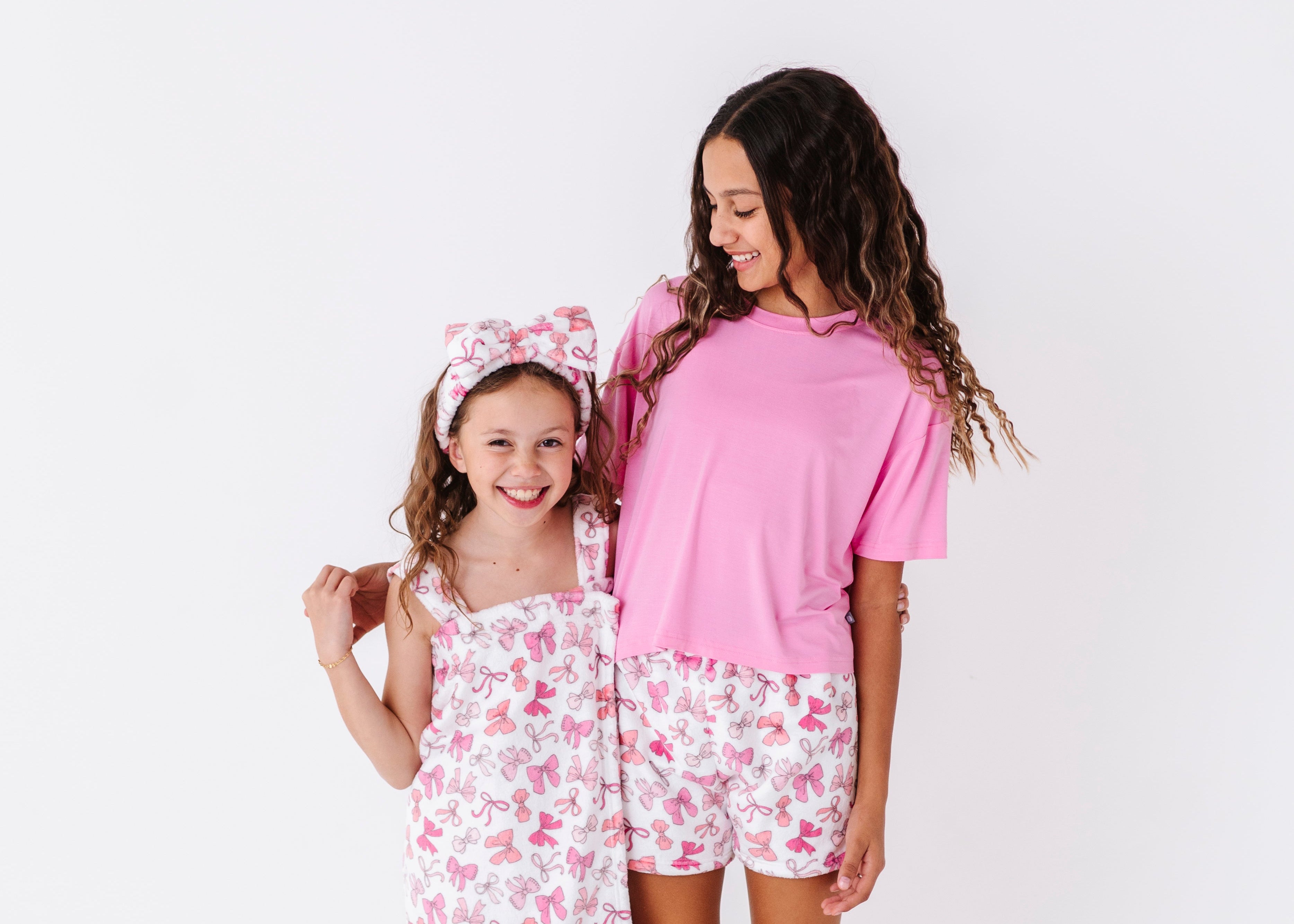 Mother and daughter wearing matching pink floral pajamas on a white background